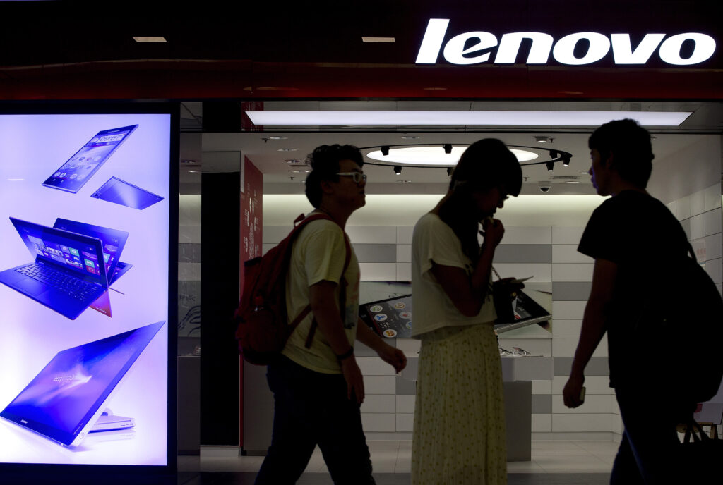FILE - In this Aug. 15, 2013 file photo, people walk past a Lenovo flagship experience store in Beijing, China. Lenovo Group has received U.S. and European approval to complete its acquisition of IBM Corp.'s low-end server business and plans to use it to grow faster outside its personal computer business, Lenovo's chairman said Monday, Sept. 29, 2014. (AP Photo/Andy Wong, File)