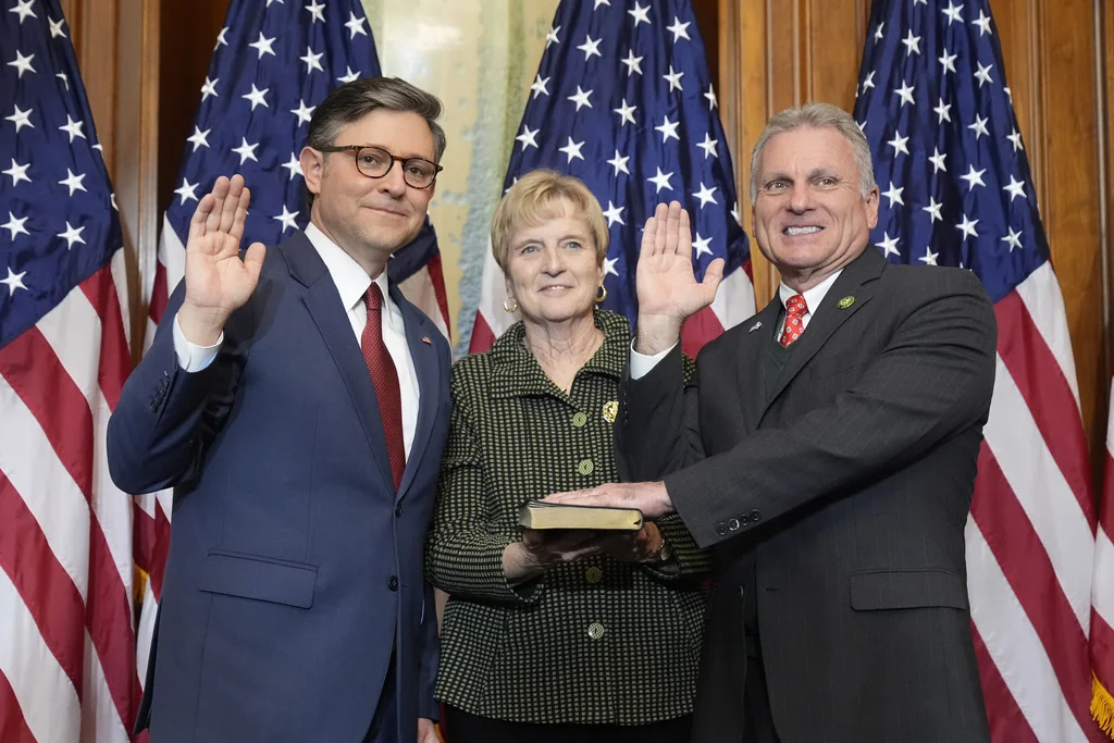 House Speaker Mike Johnson, R-La., left, poses during a ceremonial swearing-in with Rep. Buddy Carter, R-Ga., right, in the Rayburn Room at the Capitol in Washington, Friday, Jan. 3, 2025.
