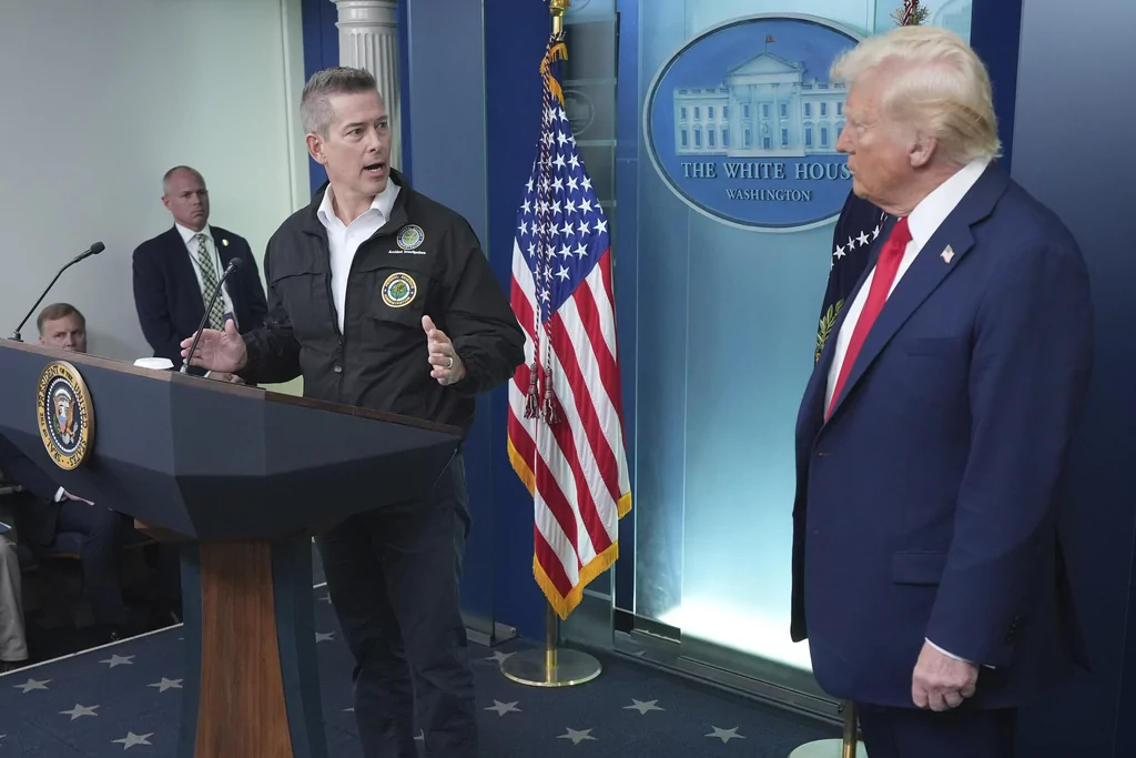 President Donald Trump stands beside Transportation Secretary Sean Duffy in the James Brady Press Briefing Room at the White House, Thursday, Jan. 30, 2025, in Washington. 