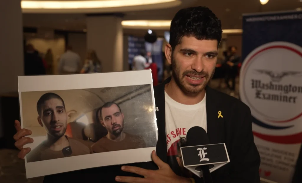 Ilay David holds up a screen grab from a Hamas propaganda video showing his brother, Evyatar, gaunt and pleading for his life.