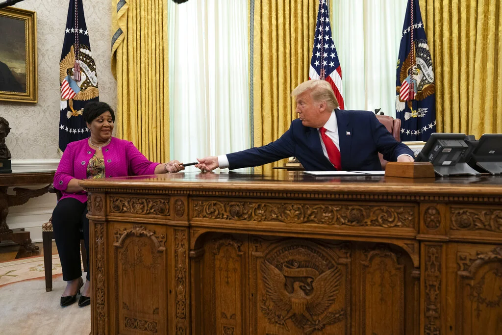 President Donald Trump hands a pen to Alice Johnson after signing a full pardon in the Oval Office of the White House, Friday, Aug. 28, 2020, in Washington.
