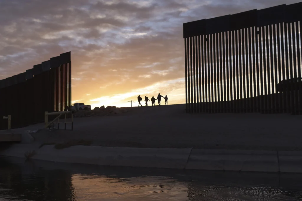 FILE - A pair of migrant families from Brazil pass through a gap in the border wall to reach the United States to seek asylum after crossing from Mexico in Yuma, Ariz., June 10, 2021. (AP Photo/Eugene Garcia, File)