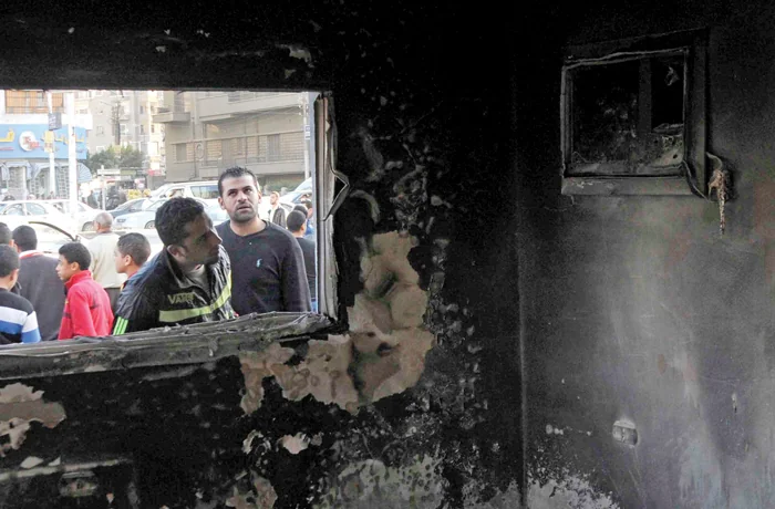 Passersby look in the windows of a police station set on fire by Muslim Brotherhood supporters in Cairo, Jan. 15, 2014. (NurPhoto/Corbis/Getty)