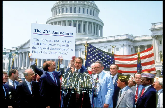A group of veterans and senators, including Sen. Robert Dole (R-KS), center, pose with the text of a proposed amendment to the U.S. constitution meant to allow bans on the burning of the American flag, June 14, 1990. (Cynthia Johnson/Getty Images)