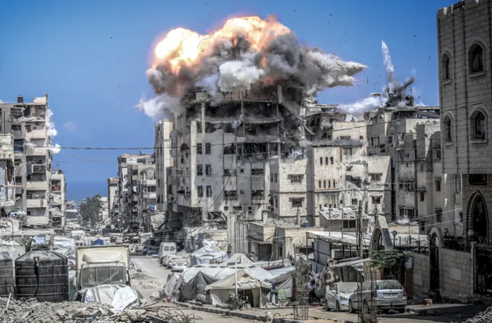A building in central Gaza is struck following a warning phone call from the Israeli army, July 21, 2025. (Saeed M. M. T. Jaras/Anadolu/Getty)