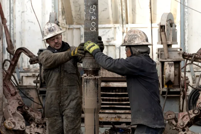 Rig operators connect drills.
