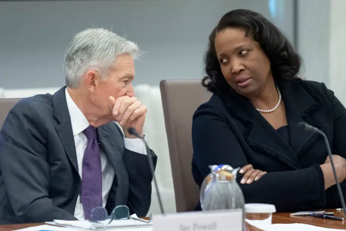 FILE - Federal Reserve Chairman Jerome Powell, left, talks with Board of Governors member Lisa Cook, right, during an open meeting of the Board of Governors at the Federal Reserve, June 25, 2025, in Washington. 