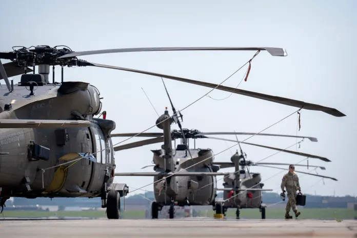 A crew member walks past U.S. Army UH-60M Black Hawk helicopters.
