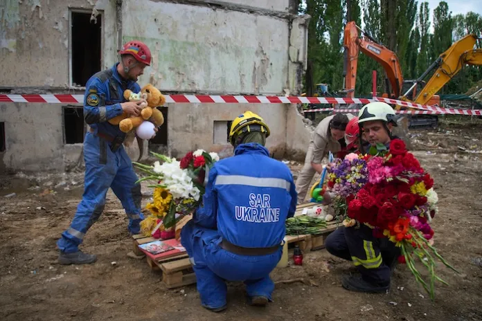 Rescuers lay toys and flowers on the site of Russia's Thursday night missile strike.