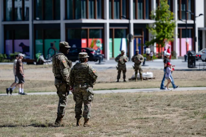 Members of the DC National Guard speak while people walk to Nationals Park, Saturday, Aug. 30, 2025, in Washington. (AP Photo/Jon Cherry)