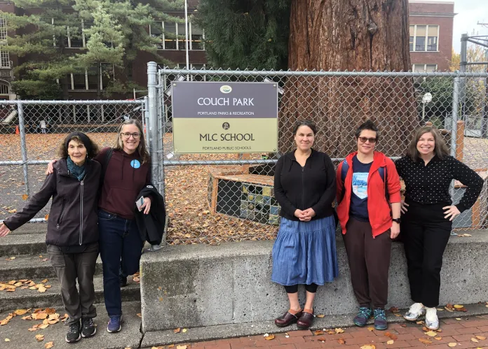 people standing in front of fence with sign