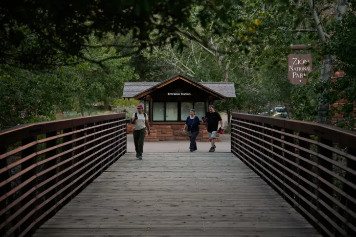 People walk by an unstaffed entrance station at Zion National Park.