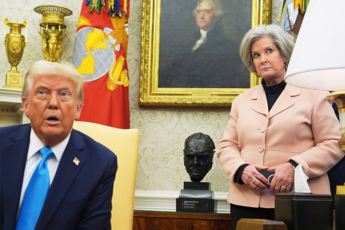 President Donald Trump speaks in the Oval Office, as White House chief of staff Susie Wiles listens behind him.