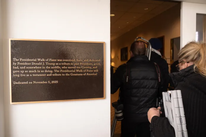Members of the press walk past a plaque near the Presidential Walk of Fame at the White House.