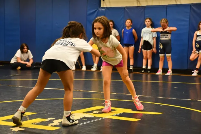 Two young girls bend down to start wrestling match.