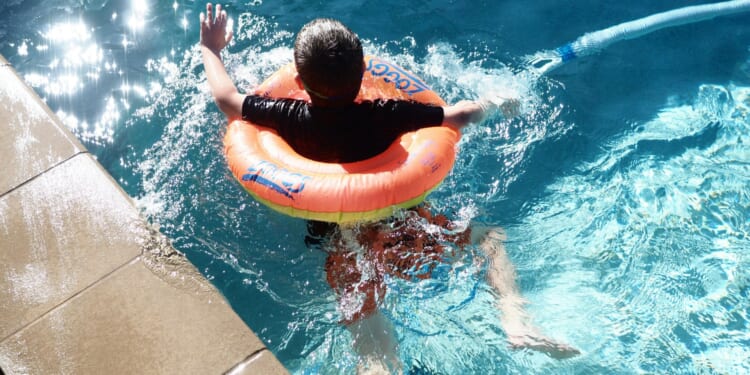 boy with floatie swims in pool
