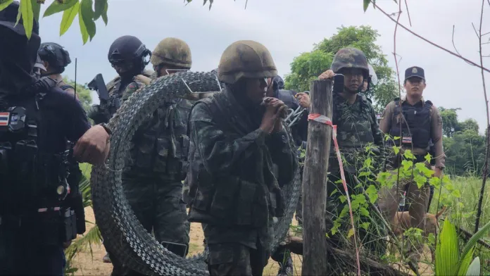 Thai soldiers carry barbed wire.