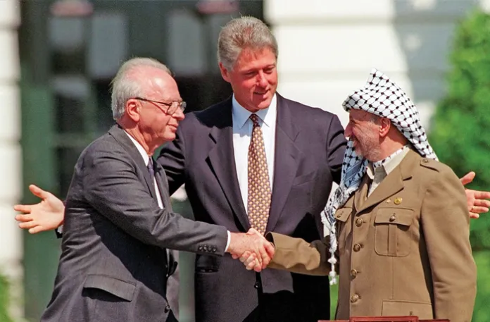 Israeli Prime Minister Yitzhak Rabin, left, and Palestine Liberation Organization Chairman Yasser Arafat, right, shake hands as President Bill Clinton looks on after the signing of the Oslo Accords on the White House lawn, Sept. 13, 1993. Under this “Declaration of Principles,” Israel recognized the PLO as the Palestinian representative, while the PLO claimed to have renounced terrorism and recognized Israel’s right to exist. (Ron Edmond /AP)