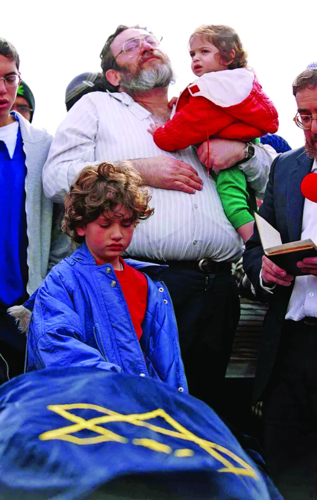 Shlomit Dudevsky, 10, puts her hand on the shroud-covered body of her mother, Hannah Dudevsky, a 39-year-old Jewish woman killed by Palestinian gunmen in a drive-by shooting during the Second Intifada, Dec. 8, 2000. (Nati Shohat/KRT/Newscom)