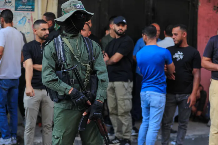 A Hamas fighter stands guard during the funeral procession of the victims of an Israeli airstrike.