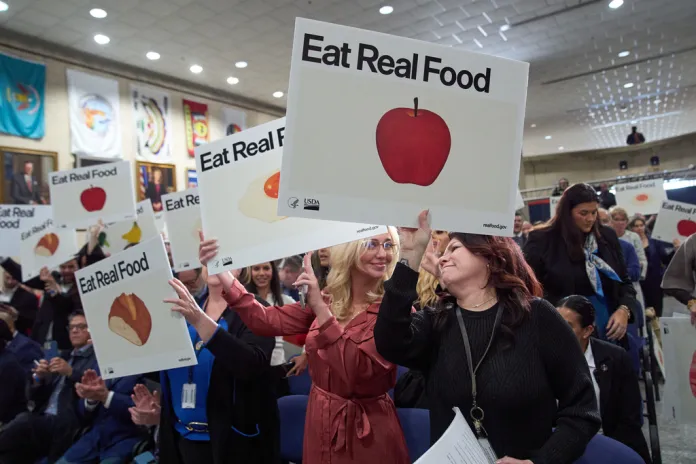 Staff and attendees of an announcement by Health and Human Services Secretary Robert F. Kennedy Jr., applause while holding drawings of foods, at Health and Human Services Headquarters, Thursday, Jan. 8, 2026, in Washington. (AP Photo/Jacquelyn Martin)