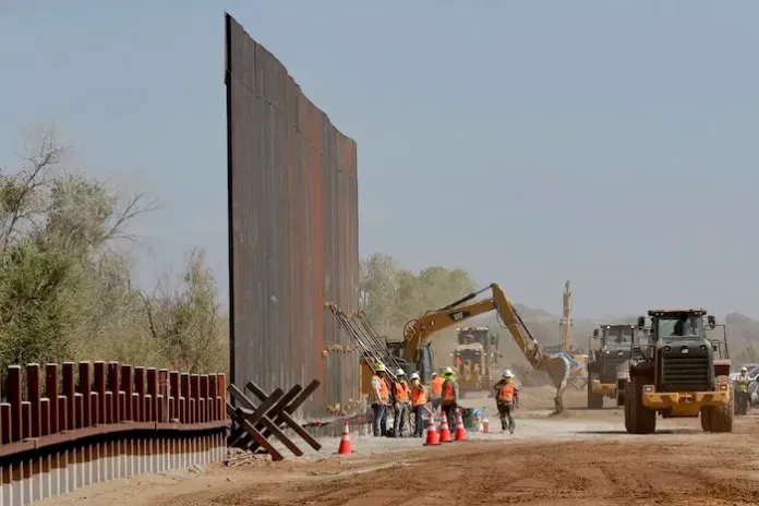 Government contractors erect a section of the Pentagon-funded border wall along the Colorado River.