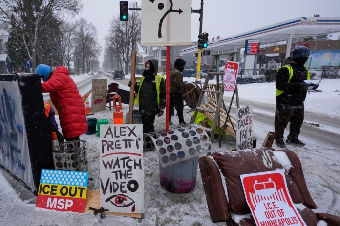 People stand near a blockade set up to deter federal immigration enforcement vehicles in Minneapolis.