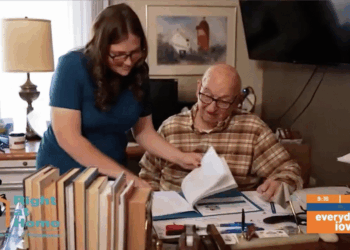 An in-home personal assistance provider helps an elderly man with paperwork.