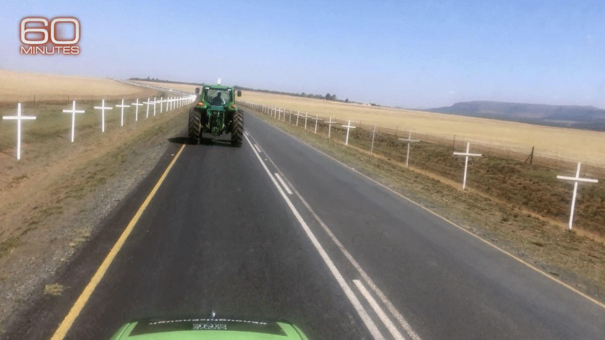 Tractor driving down the road with crosses on teh side of the road