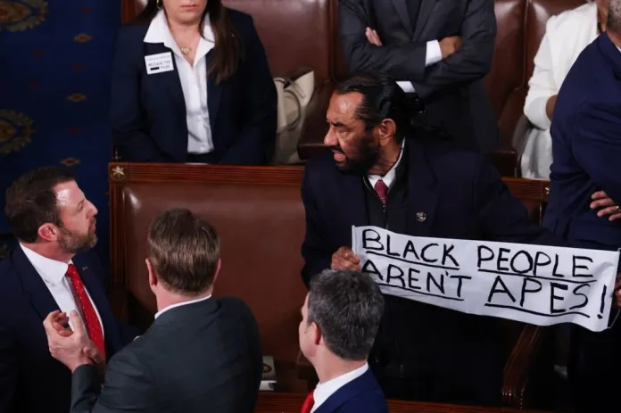 Rep. Al Green (D-TX) holds a sign with the words "Black people aren't apes!" during President Donald Trump's State of the Union.