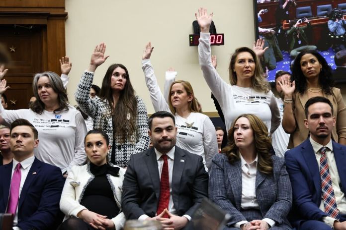Accusers of convicted sex offender Jeffrey Epstein raise their hands during Attorney General Pam Bondi's testimony before the House Judiciary Committee.