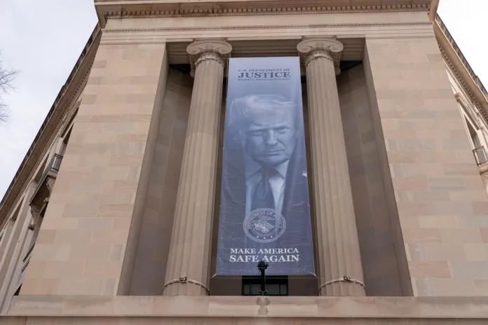 A banner with a portrait of President Donald Trump is hung from the Department of Justice, Thursday, March 5, 2026, in Washington. (AP Photo/Jose Luis Magana)