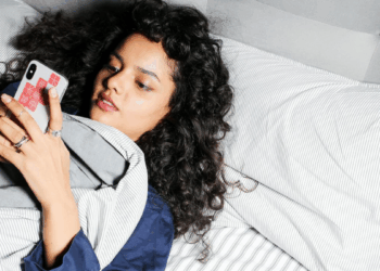 woman scrolling on phone in bed