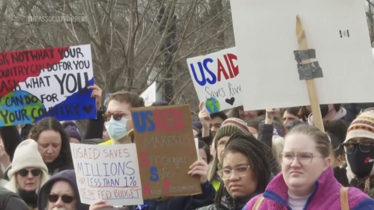 A densely packed crowd of protesters hold up signs supporting USAID.